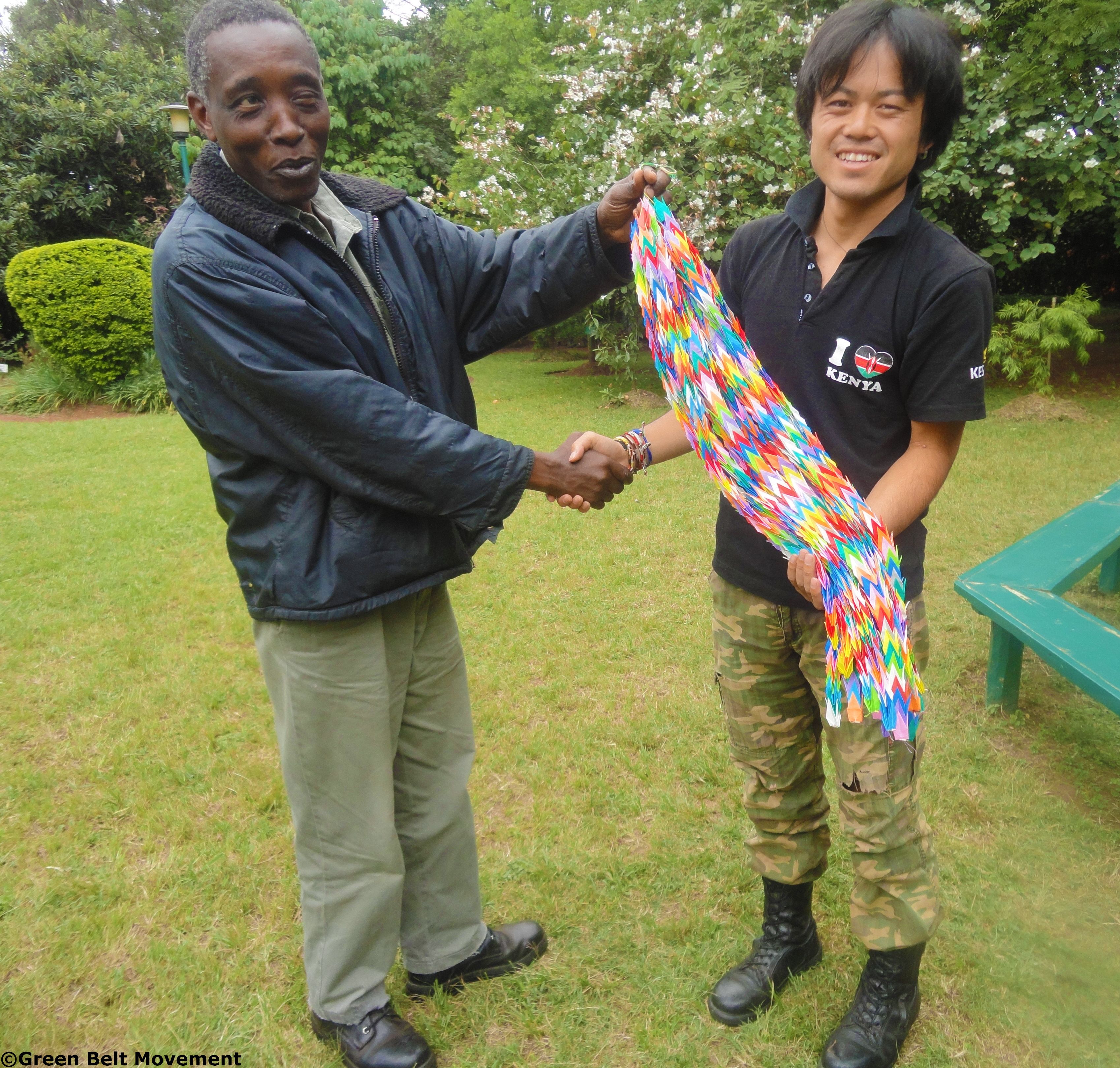 Yosumo Minato 'Maina' (right) presents the 1000 origami paper cranes to GBM's Njogu Kahare
